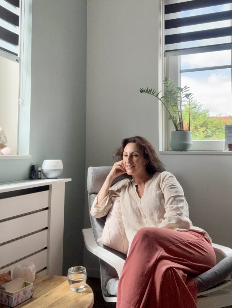 Patricia Hoefnagel ontspannen in haar praktijkruimte bij het raam